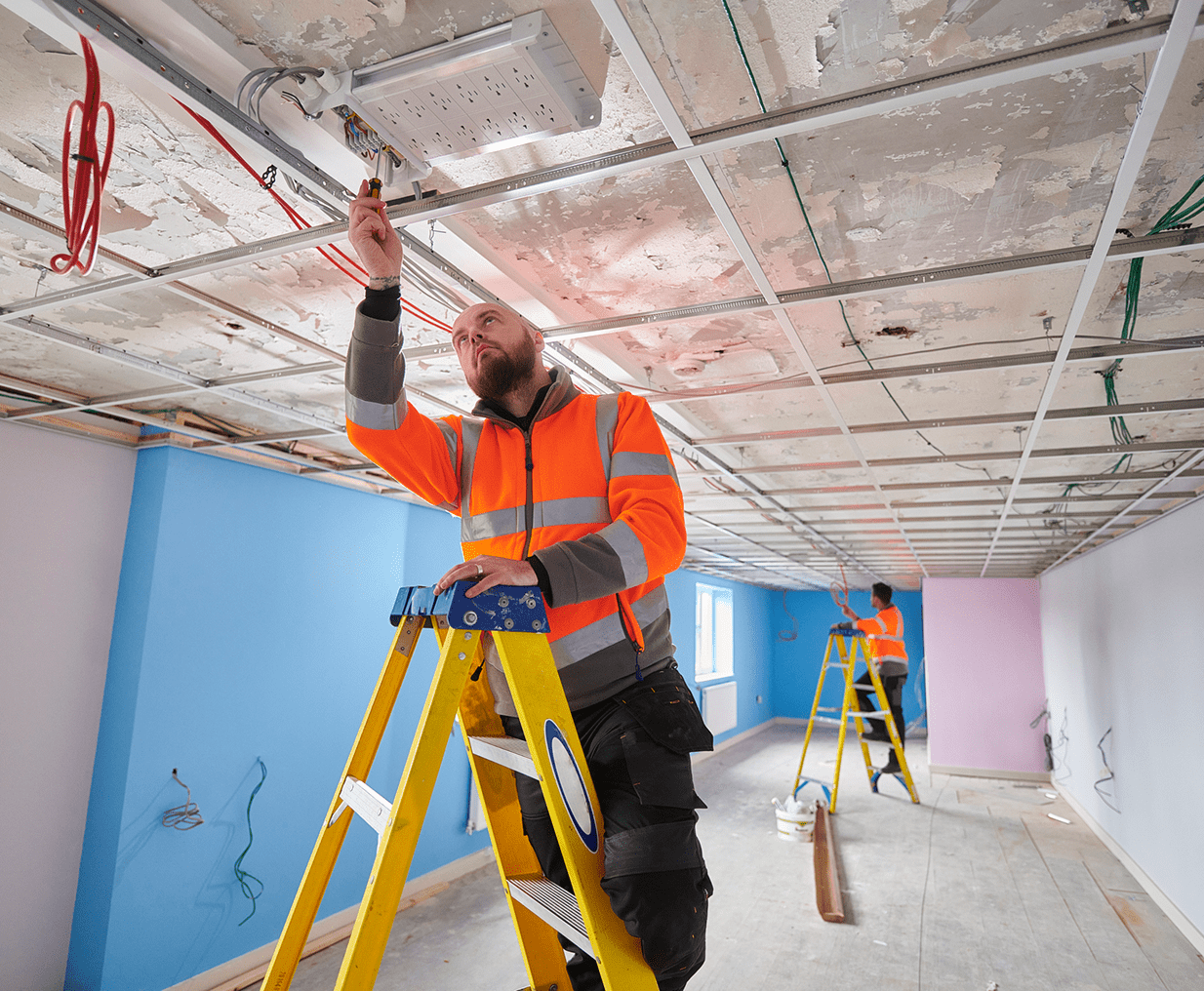 Construction workers repairing electrical wiring overhead