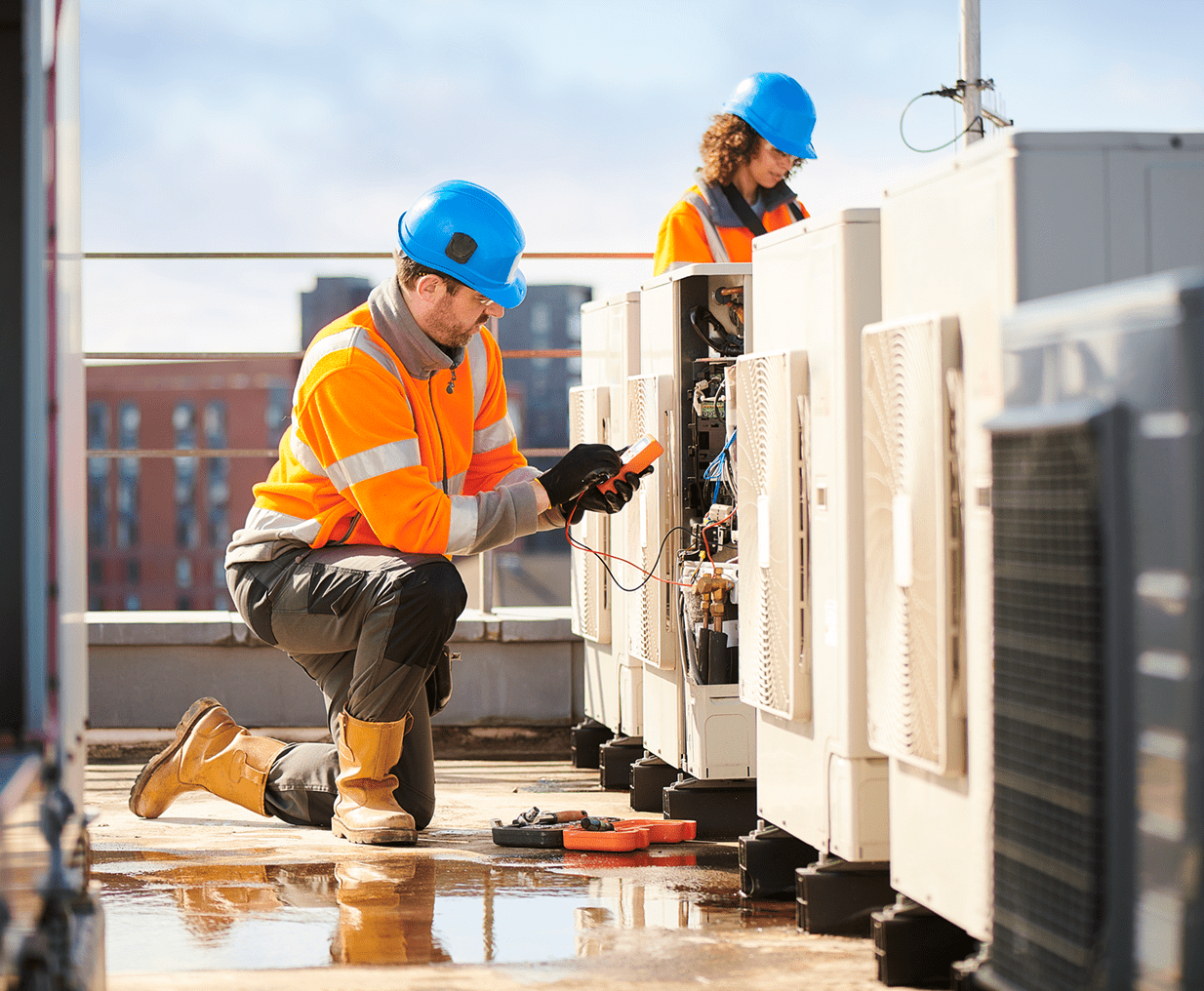 Technicians working on rooftop air conditioning units.